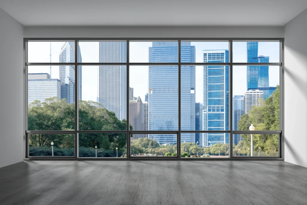 An empty office with floor-to-ceiling windows overlooking a downtown skyline