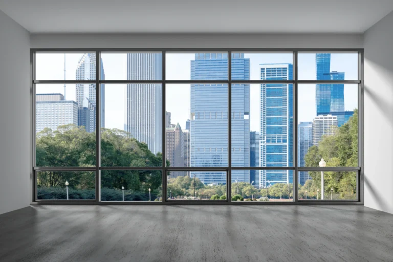 An empty office with floor-to-ceiling windows overlooking a downtown skyline
