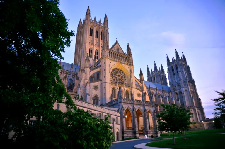 Washington National Cathedral at dusk, framed by trees